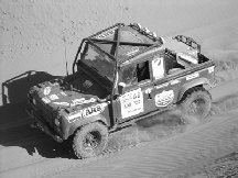 Land Rover Defender racing across dunes in Outback Challenge